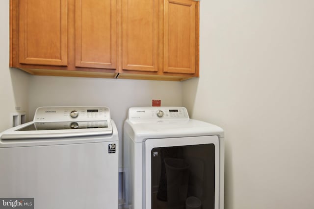 washroom featuring washing machine and clothes dryer and cabinet space
