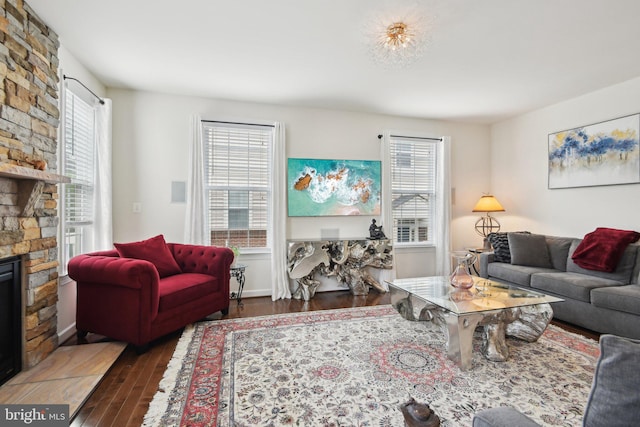 living room with hardwood / wood-style flooring, healthy amount of natural light, and a stone fireplace