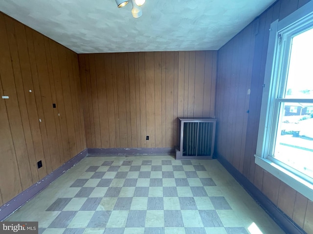 bonus room with wood walls, light flooring, and radiator heating unit