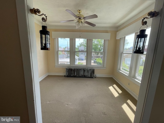 unfurnished sunroom with radiator, baseboards, and carpet