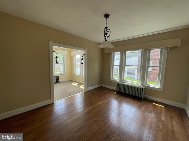 unfurnished dining area featuring radiator, wood finished floors, and baseboards