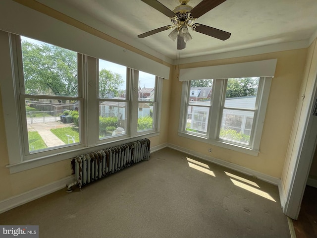unfurnished sunroom featuring radiator heating unit, healthy amount of natural light, and baseboards