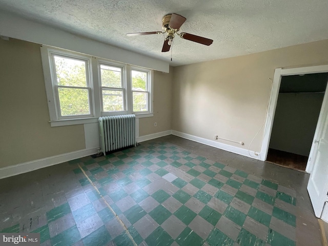 unfurnished bedroom with radiator heating unit, tile patterned floors, baseboards, a textured ceiling, and ceiling fan