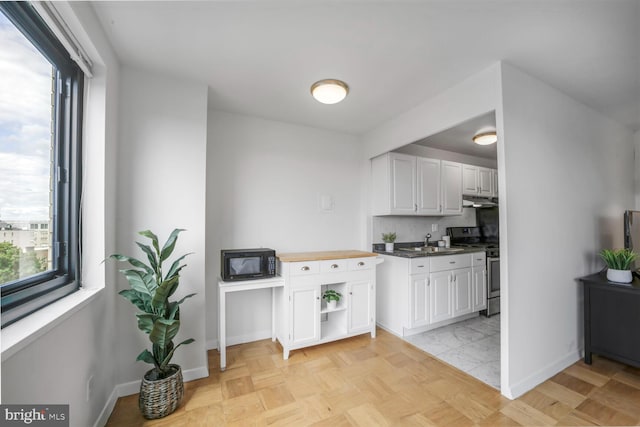 1601 18th St NW Unit 1015, Washington, DC 20009 - kitchen featuring stainless steel gas range, black microwave, a sink, under cabinet range hood, and white cabinets