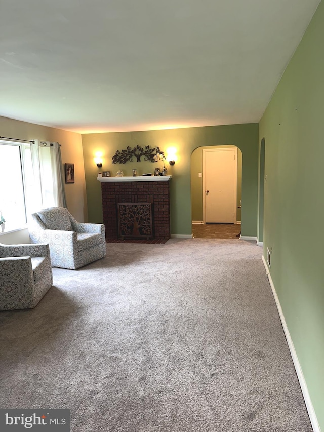 carpeted living room featuring arched walkways, a fireplace, and baseboards