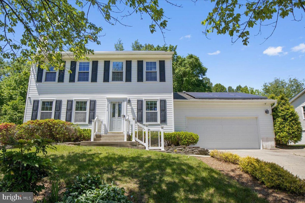 17014 Village Dr W, Upper Marlboro, MD 20772 - view of front of house featuring a front lawn, roof mounted solar panels, concrete driveway, and a garage