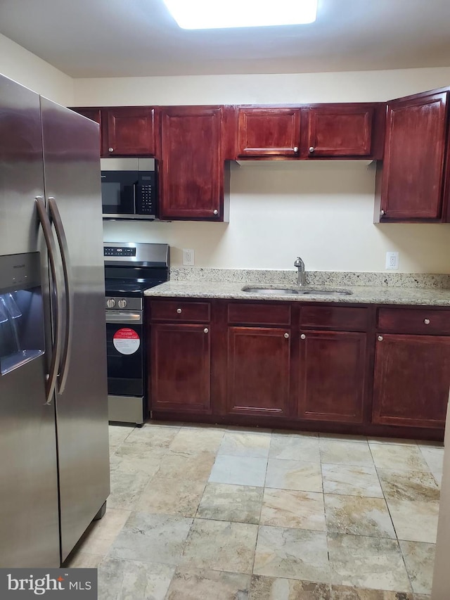 117 S Shenandoah Ave, Front Royal, VA 22630 - kitchen featuring stainless steel appliances, reddish brown cabinets, a sink, light stone finish flooring, and light stone countertops