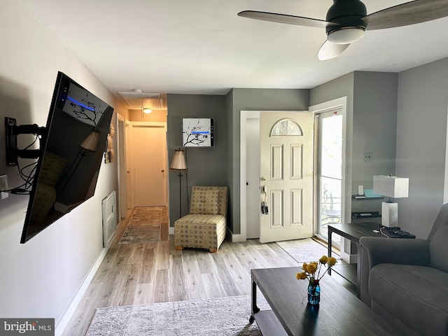 living area with light wood-style floors, baseboards, and a ceiling fan