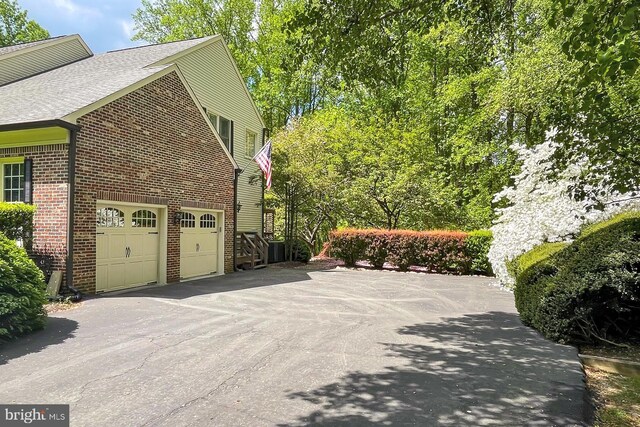 7808 Devereux Manor Ct, Fairfax Station, VA 22039 - view of home's exterior with driveway, brick siding, a garage, and roof with shingles