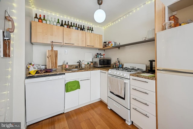 kitchen featuring white appliances, a sink, open shelves, light wood-style flooring, and dark stone counters