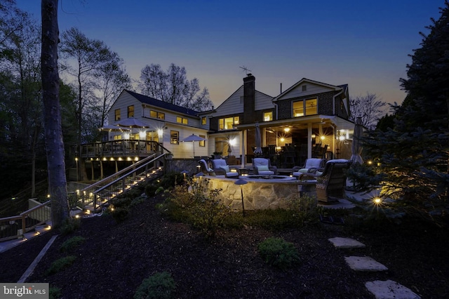 902 Emerald Dr, Alexandria, VA 22308 - back of house at dusk with a fire pit, stairway, a chimney, and a wooden deck