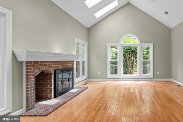 502 Pride Of Baltimore Dr, Arnold, MD 21012 - unfurnished living room featuring high vaulted ceiling, a skylight, a brick fireplace, hardwood / wood-style flooring, and baseboards