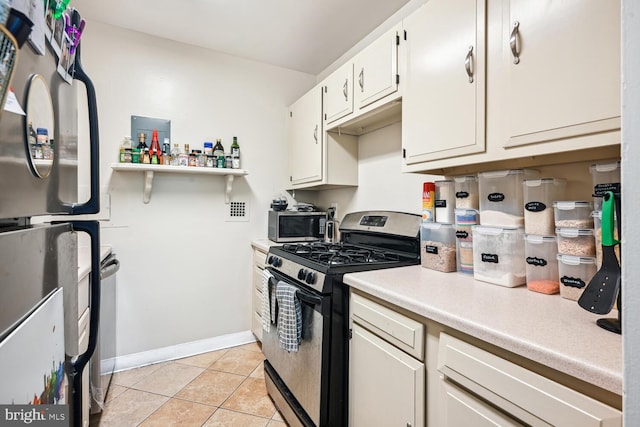 kitchen featuring appliances with stainless steel finishes, light countertops, white cabinetry, light tile patterned flooring, and baseboards