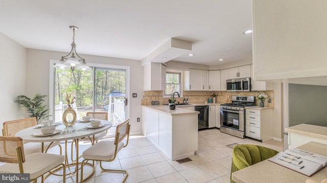 6057 English Creek Ave, Egg Harbor Township, NJ 08234 - kitchen with stainless steel appliances, white cabinets, a sink, a peninsula, and backsplash