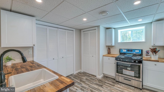 6057 English Creek Ave, Egg Harbor Township, NJ 08234 - kitchen featuring butcher block counters, stainless steel gas range, a sink, light wood-style floors, and white cabinetry