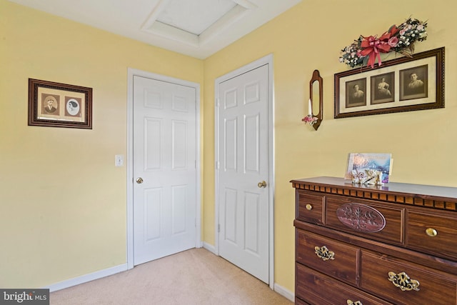 bedroom with attic access, light colored carpet, and baseboards