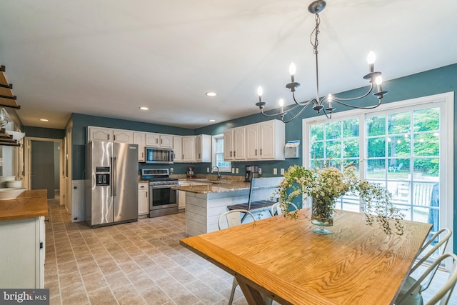 134 Whitaker Ave, North East, MD 21901 - kitchen featuring appliances with stainless steel finishes, a sink, white cabinets, a chandelier, and a peninsula