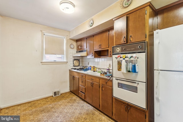 310 Passmore St, Philadelphia, PA 19111 - kitchen with white appliances, under cabinet range hood, baseboards, and brown cabinets