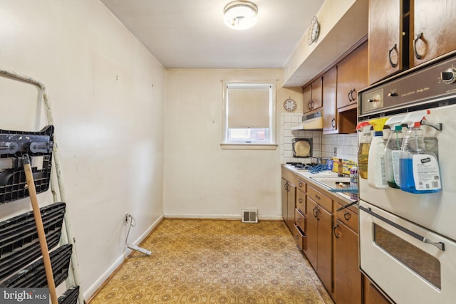 310 Passmore St, Philadelphia, PA 19111 - kitchen with white double oven, brown cabinets, decorative backsplash, under cabinet range hood, and baseboards