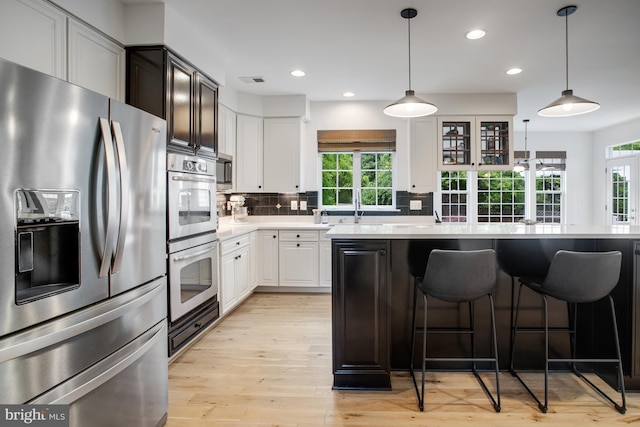 16340 Sandy Ridge Ct, Woodbridge, VA 22191 - kitchen featuring appliances with stainless steel finishes, light countertops, backsplash, a sink, and a kitchen bar