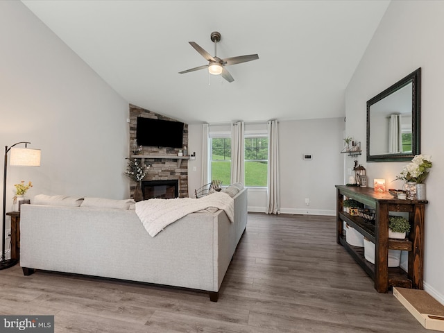 living room featuring vaulted ceiling, a fireplace, ceiling fan, wood finished floors, and baseboards