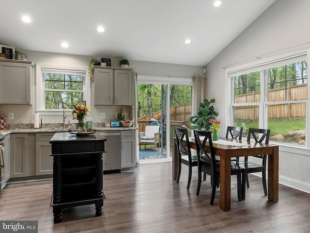 kitchen with gray cabinetry, dishwasher, a sink, lofted ceiling, and light stone countertops
