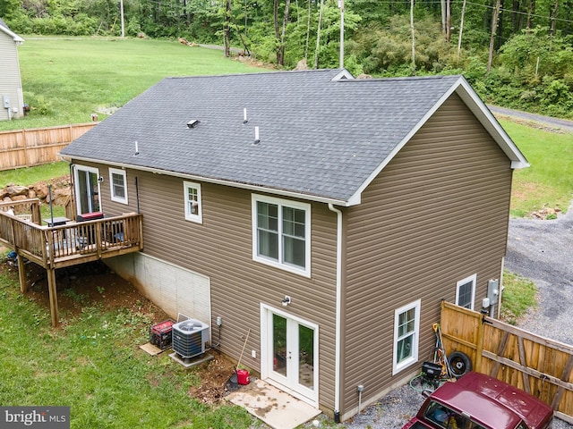 rear view of property featuring a deck, a yard, central AC unit, and roof with shingles