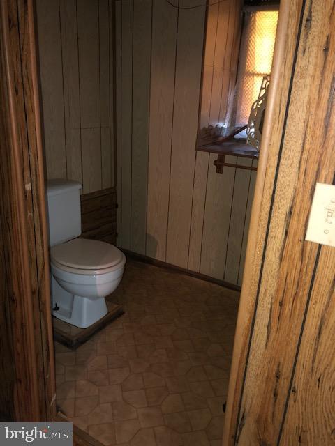 3812 Gwynn Oak Ave, Baltimore, MD 21207 - bathroom with toilet, wood walls, and tile patterned floors