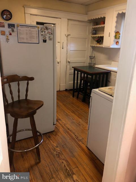 3812 Gwynn Oak Ave, Baltimore, MD 21207 - kitchen featuring freestanding refrigerator, dark wood-style flooring, washer / clothes dryer, white cabinets, and open shelves