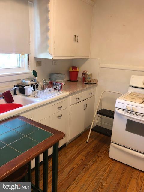 3812 Gwynn Oak Ave, Baltimore, MD 21207 - kitchen featuring white range with gas stovetop, white cabinetry, wood finished floors, and light countertops