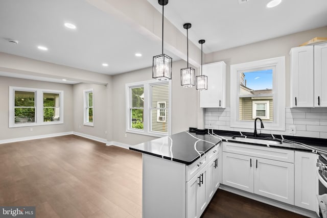 kitchen featuring dark countertops, a peninsula, decorative backsplash, open floor plan, and white cabinetry