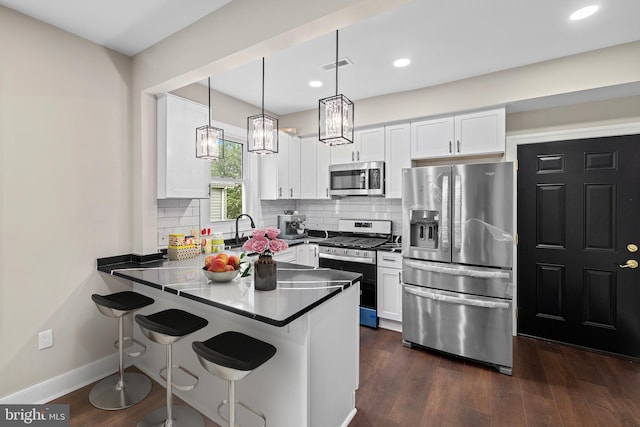 kitchen with stainless steel appliances, a peninsula, white cabinets, a kitchen breakfast bar, and recessed lighting