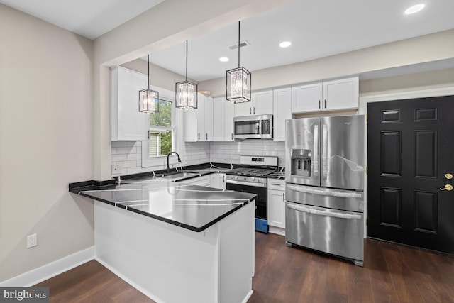 kitchen with appliances with stainless steel finishes, a sink, a peninsula, white cabinets, and recessed lighting