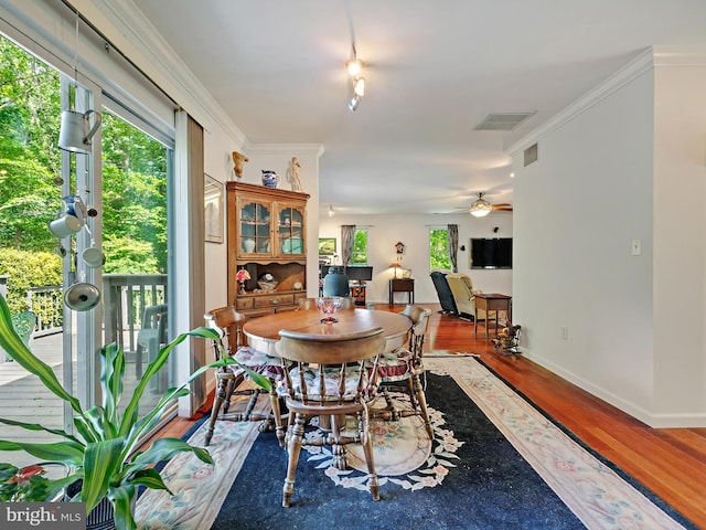 dining room featuring wood finished floors, a ceiling fan, baseboards, and ornamental molding