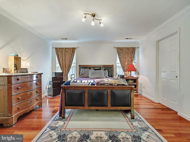 bedroom featuring multiple windows, ornamental molding, light wood-style flooring, and baseboards