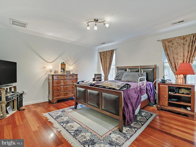 bedroom featuring crown molding, multiple windows, wood finished floors, and baseboards