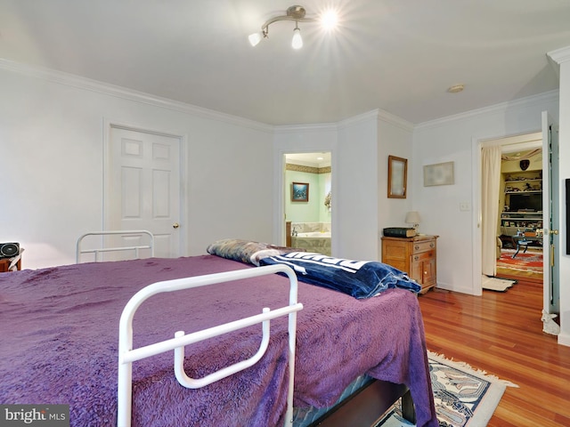 bedroom with light wood-style flooring, crown molding, and connected bathroom