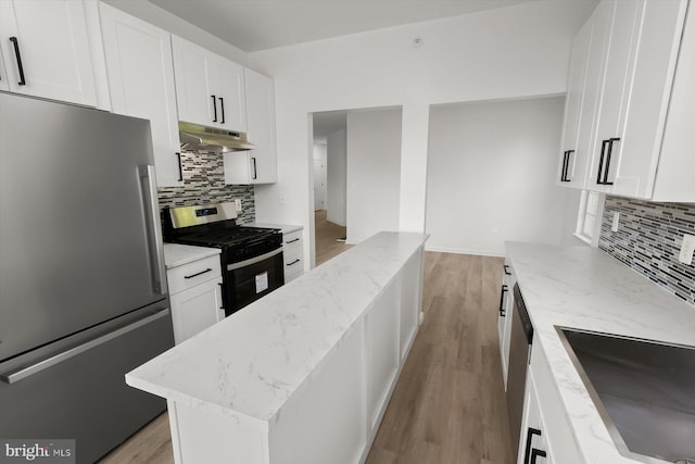 kitchen featuring stainless steel appliances, under cabinet range hood, tasteful backsplash, and light wood-type flooring