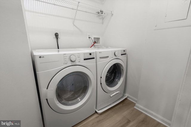 laundry area with washing machine and clothes dryer, light wood-style floors, and baseboards