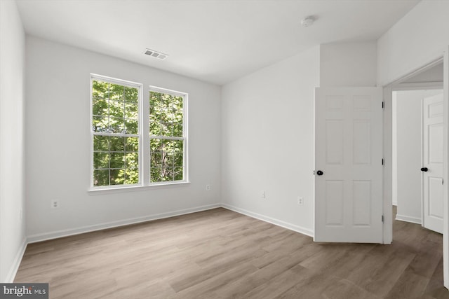 spare room with light wood-type flooring, baseboards, and a smoke detector
