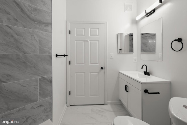 bathroom featuring marble look tiles, toilet, vanity, and baseboards