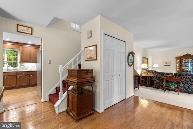 foyer with light wood finished floors, stairs, and baseboards