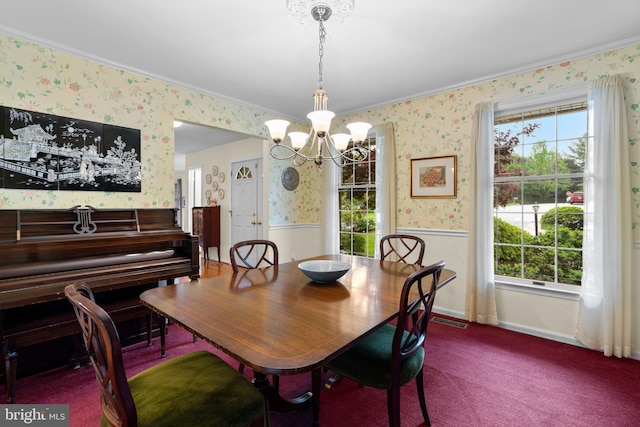 dining room with wallpapered walls, a chandelier, crown molding, and a wainscoted wall