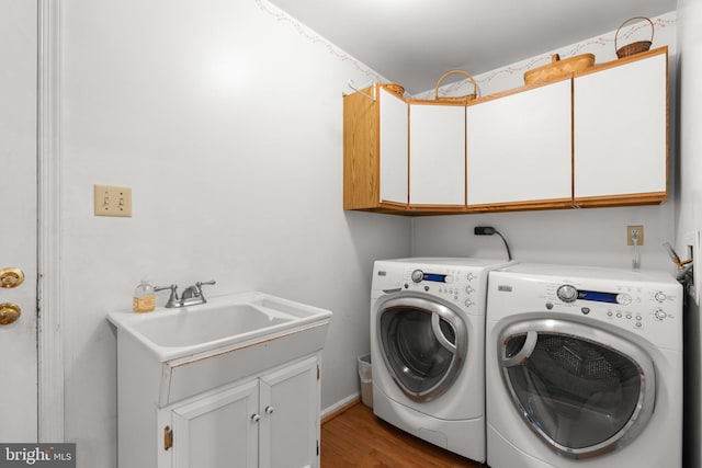washroom with cabinet space, washing machine and dryer, and wood finished floors