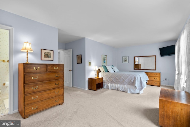 bedroom featuring light carpet, baseboards, and ensuite bath