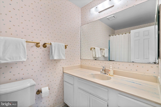 bathroom with wallpapered walls, toilet, vanity, and a shower with curtain