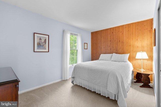 carpeted bedroom featuring wooden walls and baseboards