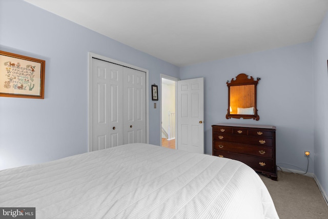 carpeted bedroom featuring a closet and baseboards