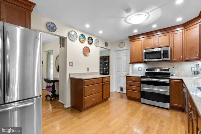 kitchen featuring appliances with stainless steel finishes, light wood-style flooring, brown cabinets, recessed lighting, and backsplash