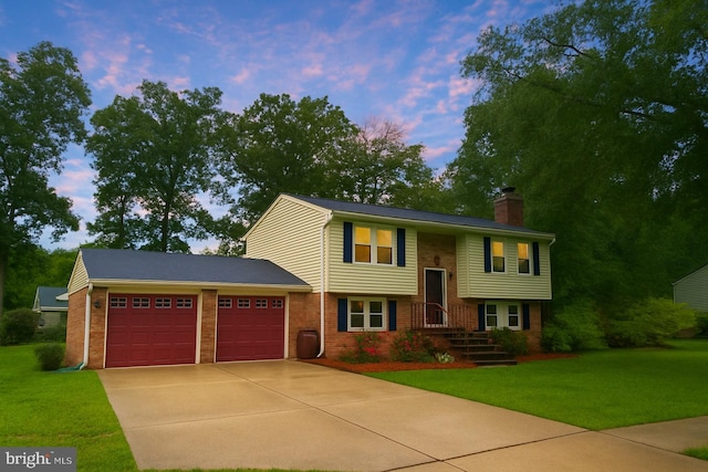 bi-level home featuring an attached garage, driveway, brick siding, a front lawn, and a chimney